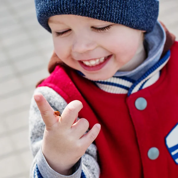 Criança sorrindo criança olhando para uma joaninha — Fotografia de Stock