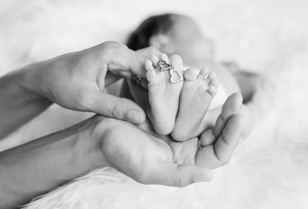 Leg of the newborn child in caring hands — Stock Photo, Image