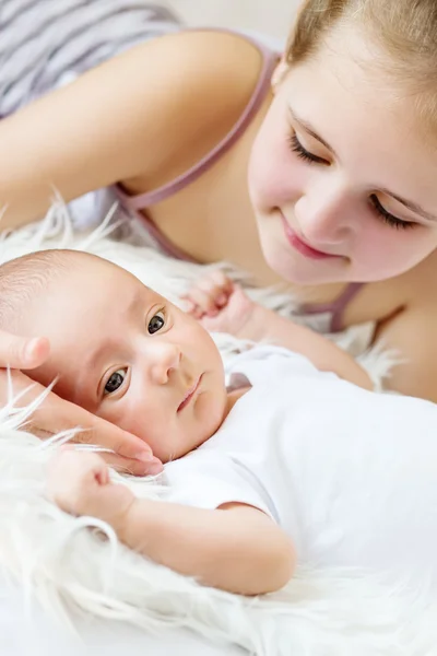 Cute little sister looks at newborn — Stock Photo, Image
