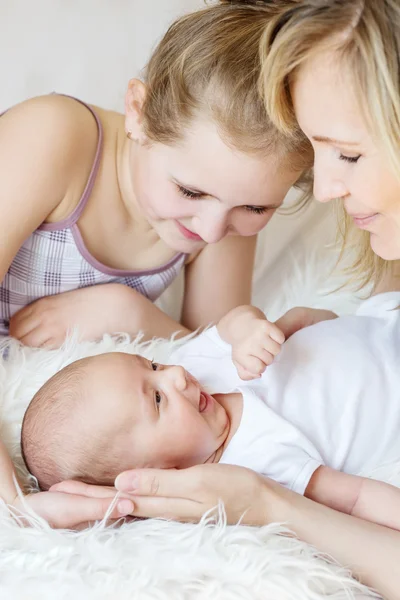 Счастливая мать и дочь улыбаются, глядя на новорожденного — стоковое фото