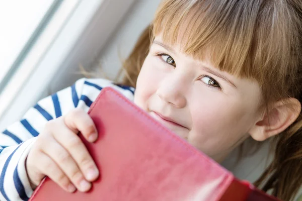 Glückliches kleines Mädchen mit einem Buch in der Hand — Stockfoto