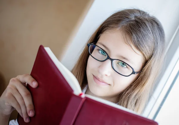 Cute schoolgirl in glasses holding a book — Stock Photo, Image