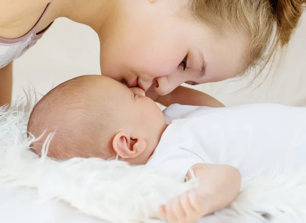 Cute little sister kisses newborn — Stock Photo, Image