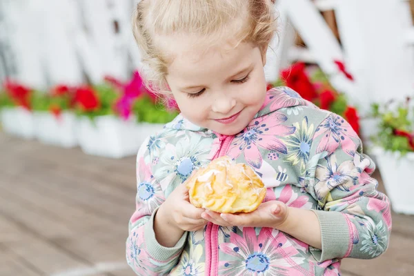 Carino bambina mangiare eclair — Foto Stock