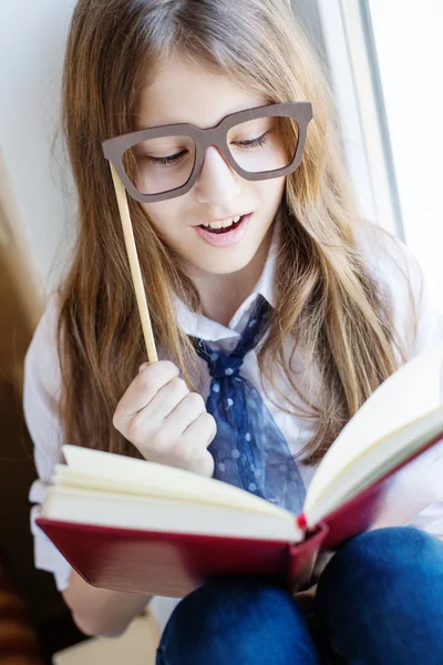 Cute schoolgirl in glasses holding a book — Stock Photo, Image