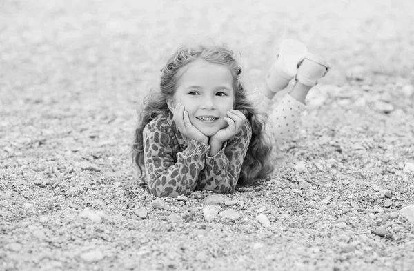 Çakıl taşları üzerinde yalan mutlu küçük kız — Stok fotoğraf