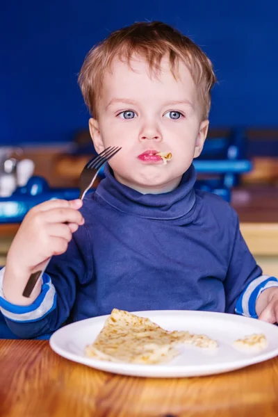 Menino em um café comendo uma panqueca — Fotografia de Stock