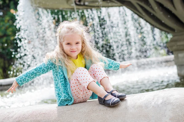 Schattig klein meisje spelen met een fontein stad — Stockfoto