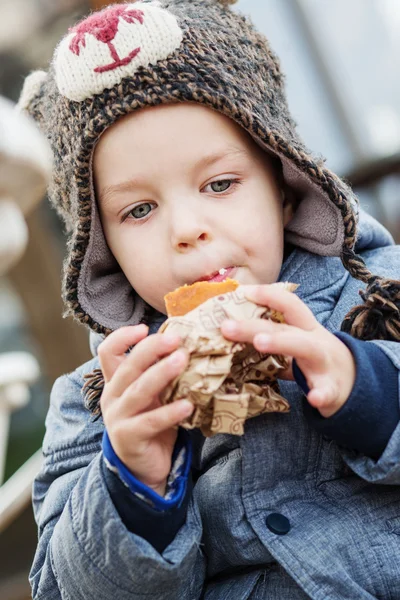 Bonito pequeno menino comer bolo ao ar livre — Fotografia de Stock