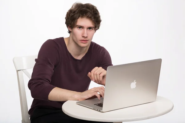 Retrato de chico joven inteligente surfeando en el ordenador portátil mientras está sentado en la silla — Foto de Stock