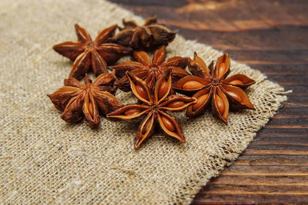 Dry seasoning anise on a linen napkin and on a brown wooden background close-up, the concept of spices and aromatic seasonings, cooking and drinks, Christmas baking