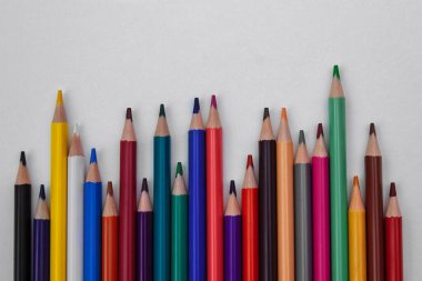 Açık gri kağıt arkaplan üzerinde kapalı renkli kalemler. Metin için boş bir alan, okula geri dönme konsepti, çocukların yaratıcılığı ve gelişimi, iyi motor becerileri ve ev ödevleri.