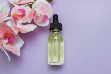 Pembe arka planda pipeti olan kozmetik cam yağ şişesi. Metin, kapanış, cilt bakımı ve tedavi konsepti, yüz vitaminleri, gençleştirme, sivilce ve sivilceler için boş yeri olan orkide çiçekleri.
