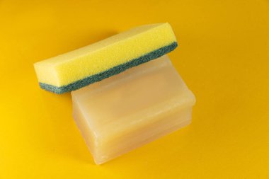 Sarı arka planda mutfak süngeri ve sabun.