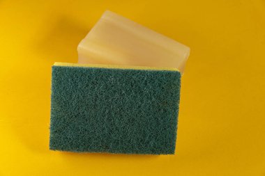 Sarı arka planda mutfak süngeri ve sabun.