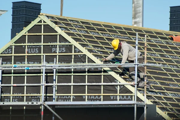 職人は、屋根の上の作業します。彼は黄色の安全保護ヘルメットをかぶってください。. — ストック写真