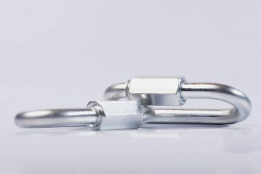 Metal kopçaları, izole edilmiş beyaz bir zemine takılıyor. Paslanmaz çelikten yapılmış karabina, hızlı kilidi olan ağır karabina.. 