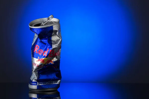 Lata Red Bull Arrugada Con Gotitas Agua Sobre Fondo Azul Fotos de stock libres de derechos