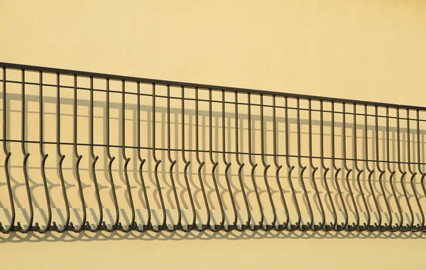 Декоративный металлический забор с тенью на стене — стоковое фото