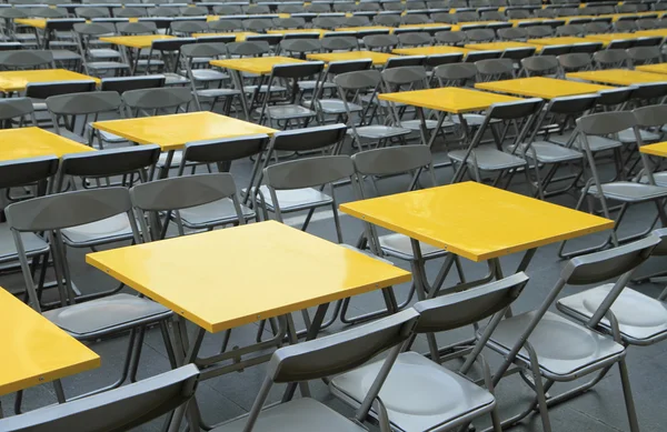 Rows of yellow metal tables and chairs