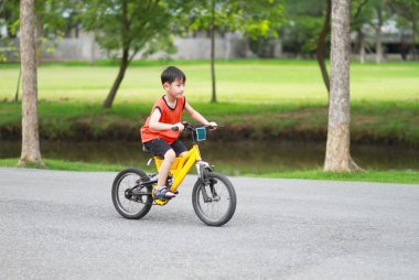 Parkta bisiklet süren Asyalı çocuk.