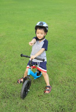 Asyalı çocuk binicilik bisiklet yeşil sahada