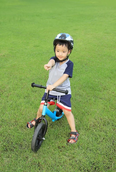 Ásia menino equitação bicicleta no verde campo — Fotografia de Stock