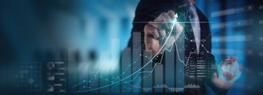 Modern bilgisayar sanal gösterge paneli ile çalışan işadamı finans satış verilerini ve ekonomik büyüme grafiklerini analiz ediyor ve zincir teknolojisini engelliyor.