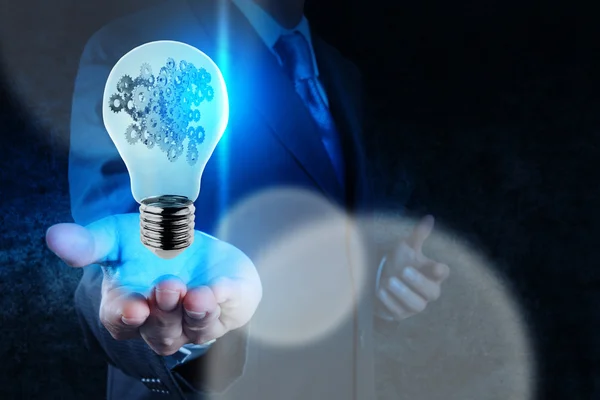 Businessman hand showing light bulb with gears as concept — Stock Photo, Image