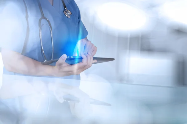Doutor trabalhando com computador tablet em fundo azul — Fotografia de Stock