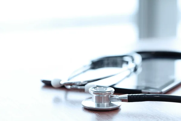 Stethoscope with digital tablet computer on wooden table and  ba — Stock Photo, Image