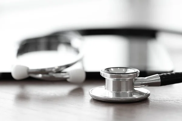 Stethoscope with digital tablet computer on wooden table and  ba — Stock Photo, Image