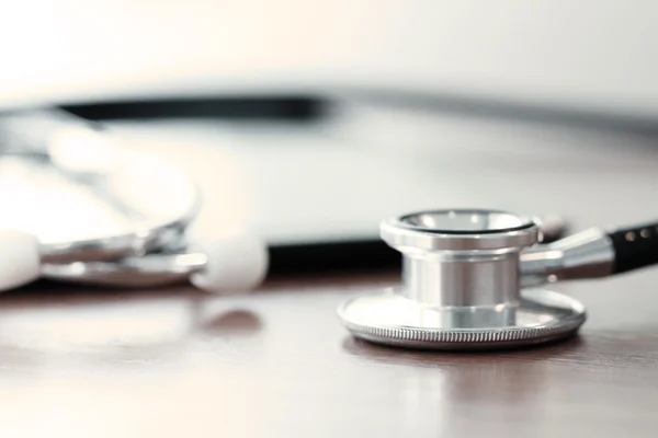 Stethoscope with digital tablet computer on wooden table and  ba — Stock Photo, Image