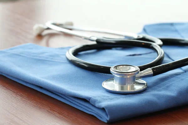 Stetoskop z lekarza niebieski płaszcz na drewnianym stole z płytkich D — Zdjęcie stockowe