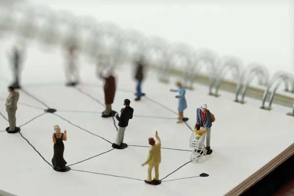 Close up of miniature people with social network diagram on open — Stock Photo, Image