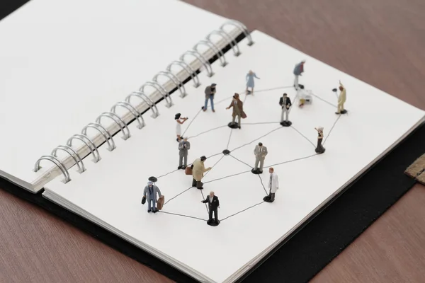 Close up of miniature people with social network diagram on open — Stock Photo, Image