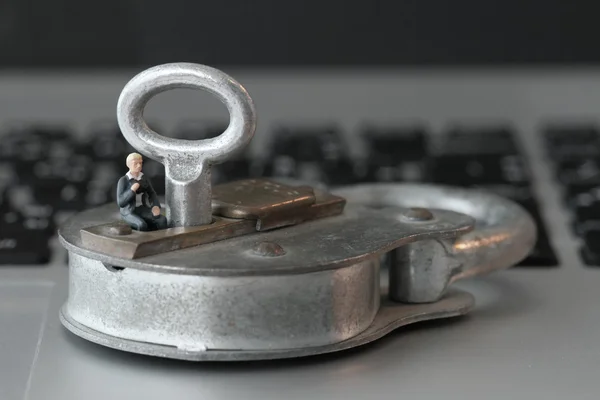 Internet-Sicherheitskonzept-Miniatur-Geschäftsmann sitzt auf altem Schlüssel — Stockfoto