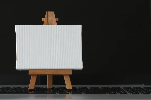Tela bianca e cavalletto in legno sul computer portatile come concetto — Foto Stock