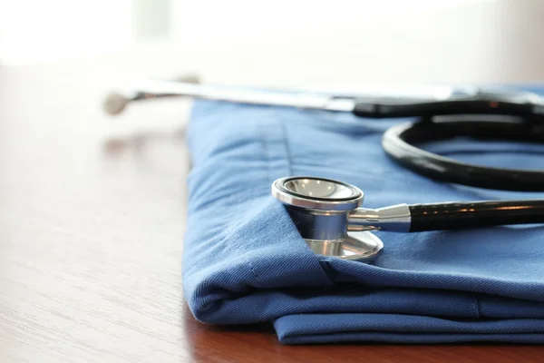 Estetoscópio com casaco médico azul na mesa de madeira com D raso — Fotografia de Stock