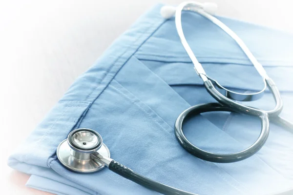 Stethoscope with blue doctor coat on wooden table with shallow D — Stock Photo, Image