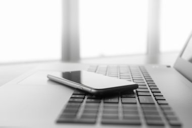 Ofis işyeri dizüstü bilgisayar ve ahşap masa üstünde smartphone