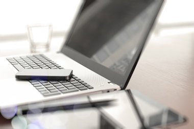 Ofis işyeri dizüstü bilgisayar ve ahşap masa üstünde smartphone