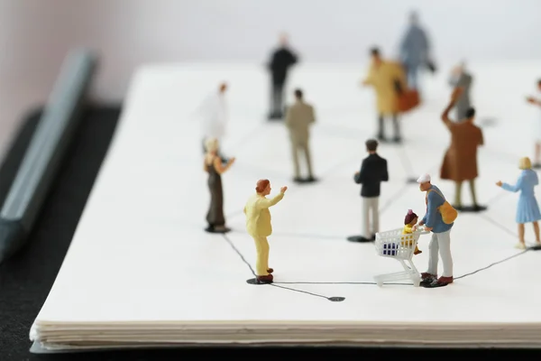 Close up of miniature people with social network diagram on open — Stock Photo, Image