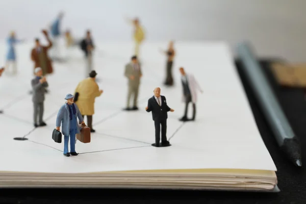 Close up of miniature people with social network diagram on open — Stock Photo, Image