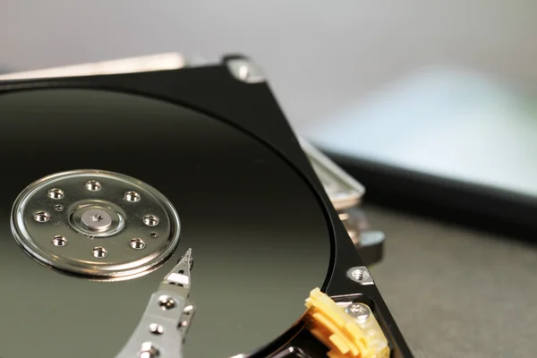 Close up of open computer hard disk drive on desk and notebook — Stock Photo, Image