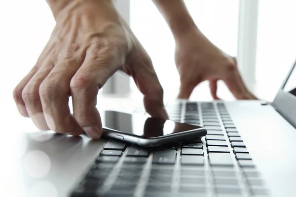 Main d'homme d'affaires en utilisant un ordinateur portable et un téléphone mobile dans le bureau — Photo