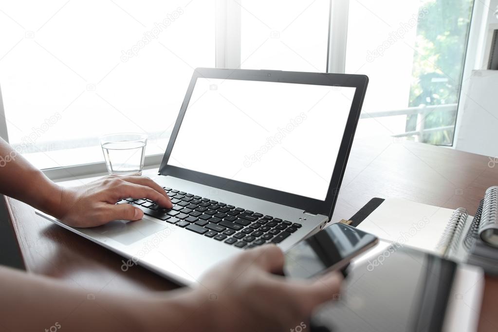 Businessman hand using laptop and mobile phone in office