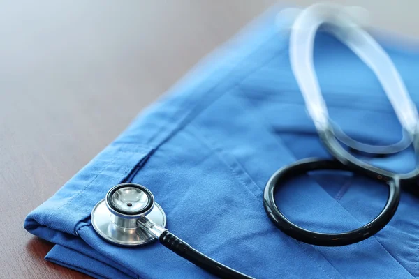 Stethoskop mit blauem Arztkittel auf Holztisch mit flachem d — Stockfoto