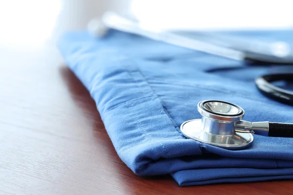 Estetoscópio com casaco médico azul na mesa de madeira com D raso — Fotografia de Stock