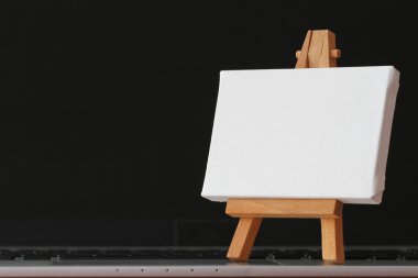 boş tuval ve ahşap şövale üzerinde dizüstü bilgisayar kavram olarak